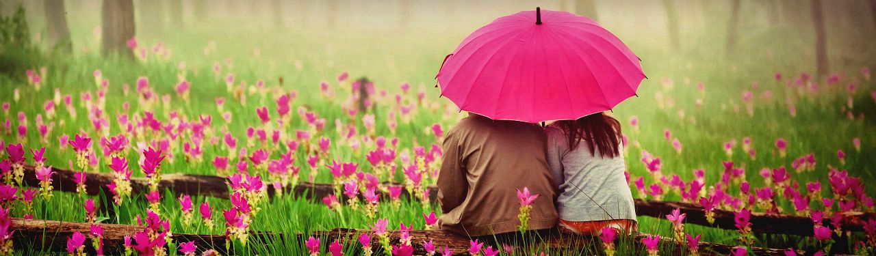 cute-couple-with-umbrella-in-blossom-field-web-header